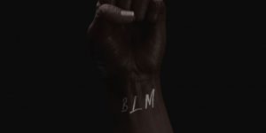 Photo of a raised fist with BLM on the wrist.