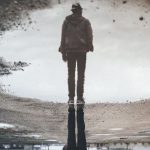 Image of a man reflected in a puddle.