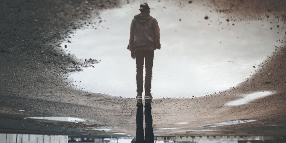 Image of a man reflected in a puddle.