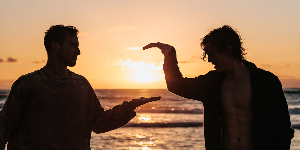 Two men about to shake hands in the sunset.