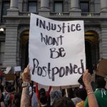 "Injustice Won't Be Postponed" sign