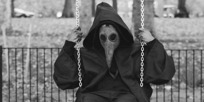 A man in a plague mask on a swing