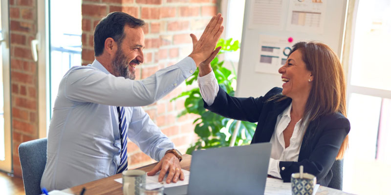 A man and woman high five in an office