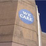 A brutalist building with a "We Care" sign