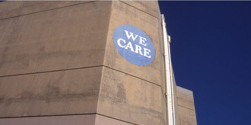 A brutalist building with a "We Care" sign