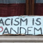 Sign reading "Racism Is A Pandemic"