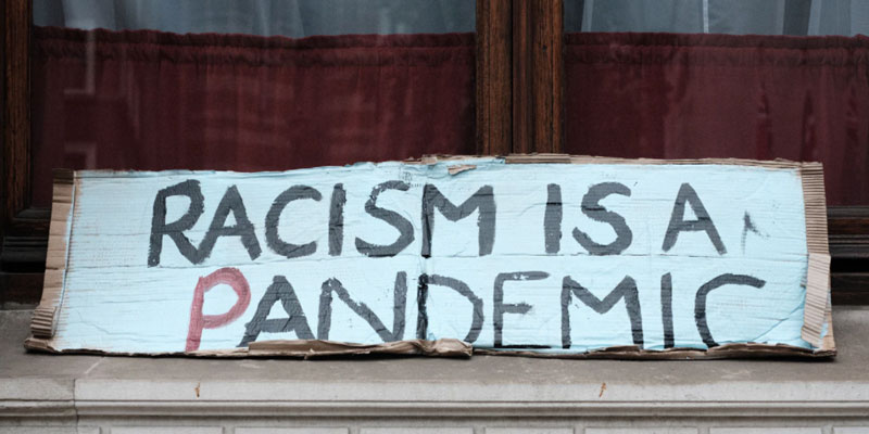 Sign reading "Racism Is A Pandemic"