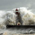 A wave engulfs a lighthouse