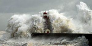 A wave engulfs a lighthouse