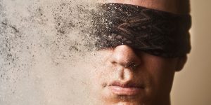 A blindfolded man disintegrating