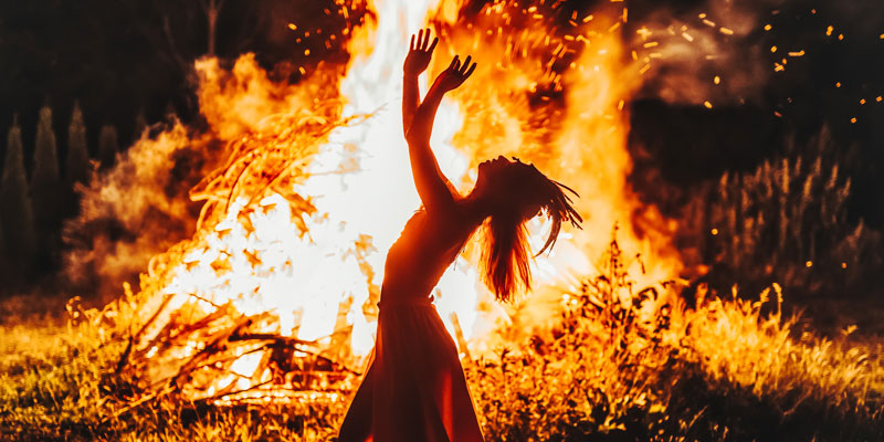 A woman dances around a fire