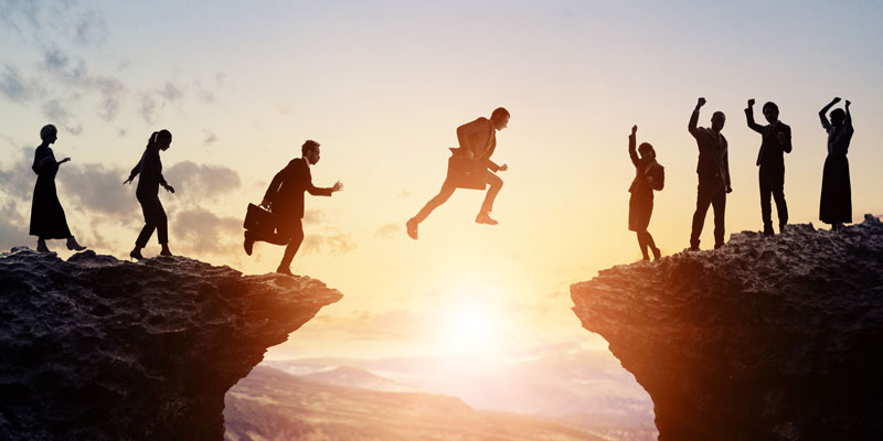 Business people leap over a chasm.
