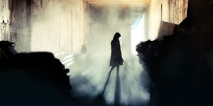 A woman walks in a smokey alley